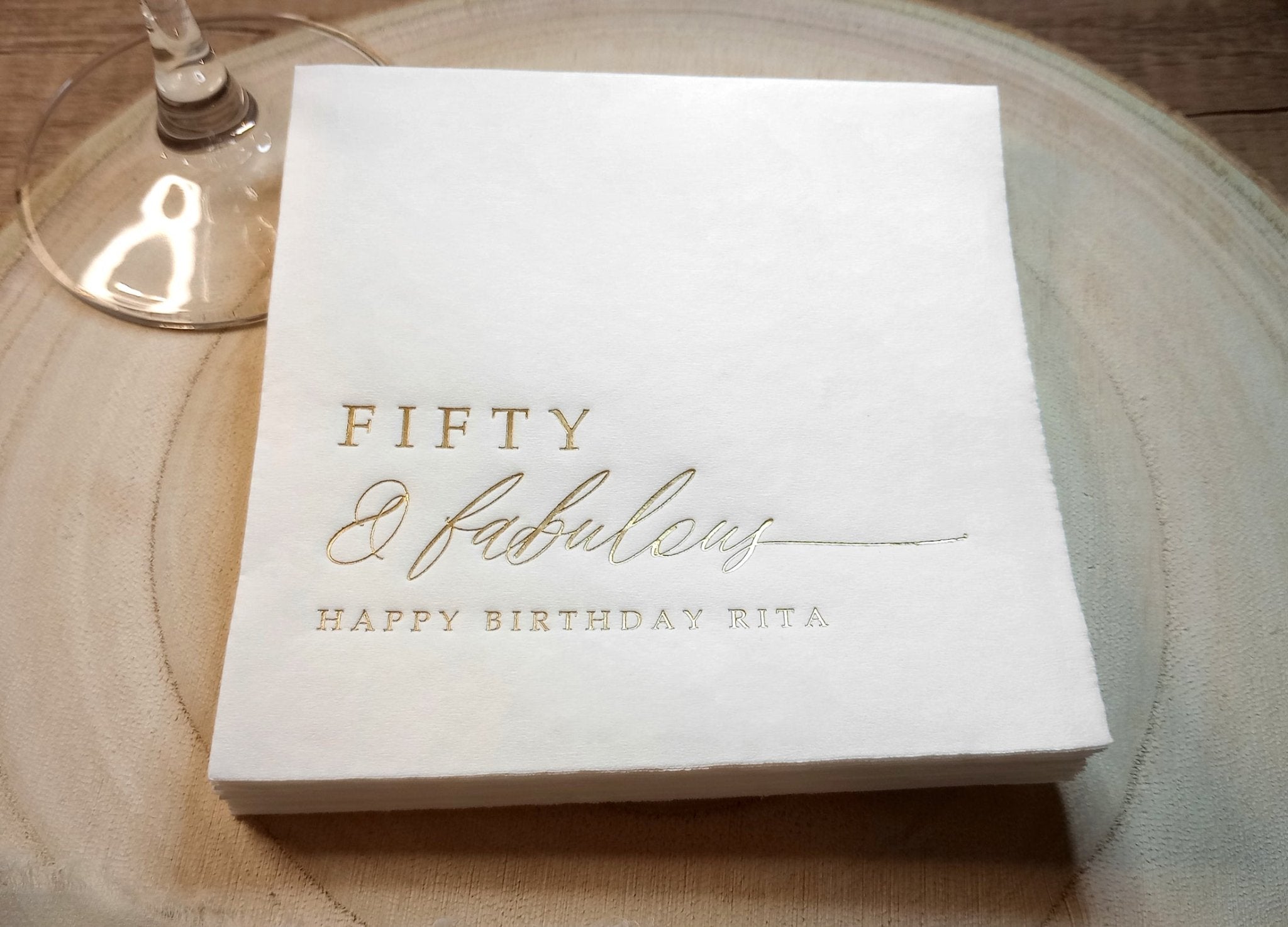 Close-up of foil-stamped “Fifty & Fabulous” napkin with name and birthday message