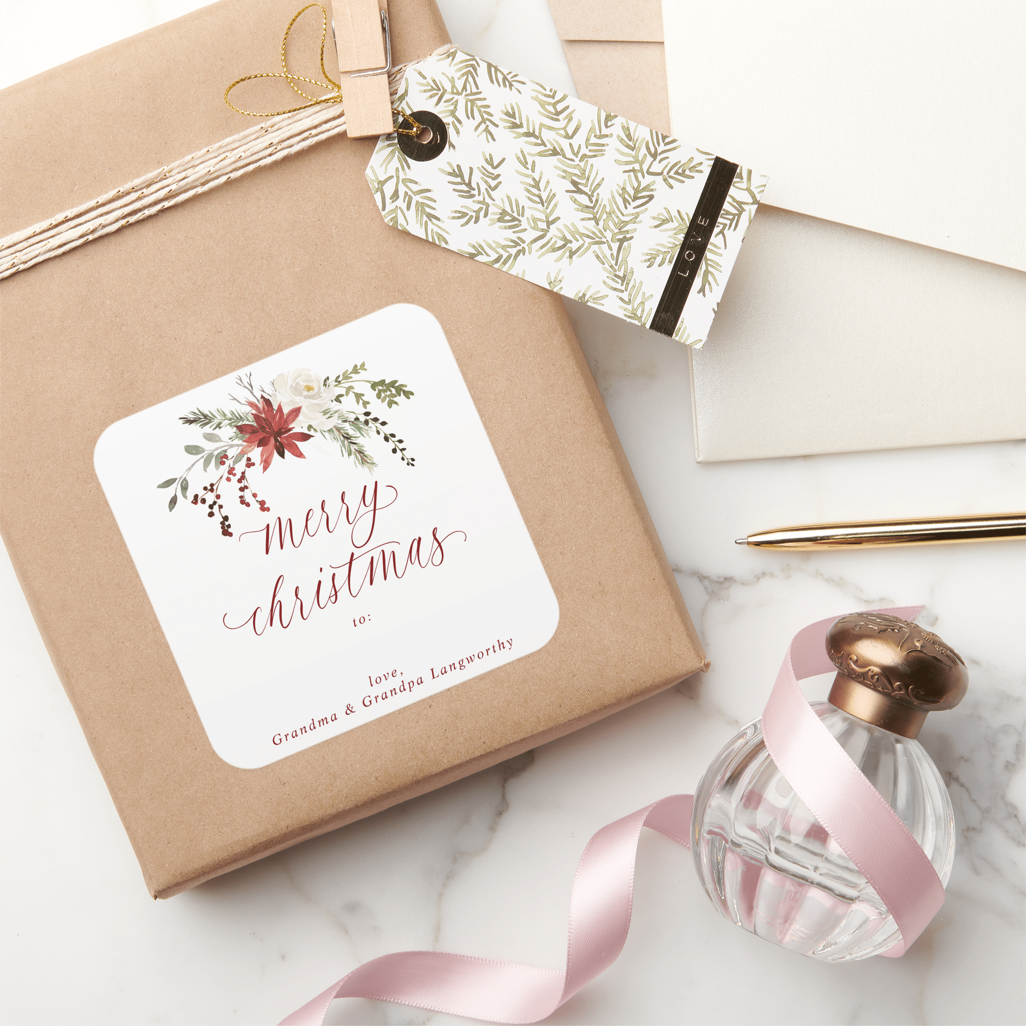 Gift box with an elegant 'Merry Christmas' tag, pink ribbon, and perfume bottle on a marble surface.
