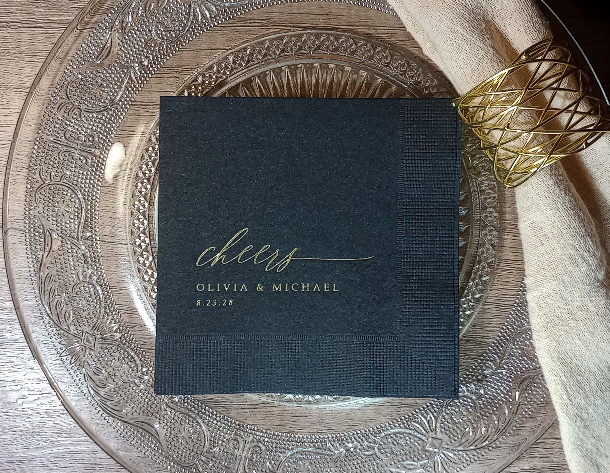 Elegant black wedding napkins with gold “cheers” script — modern, simple, and timeless for the bride and groom’s celebration.