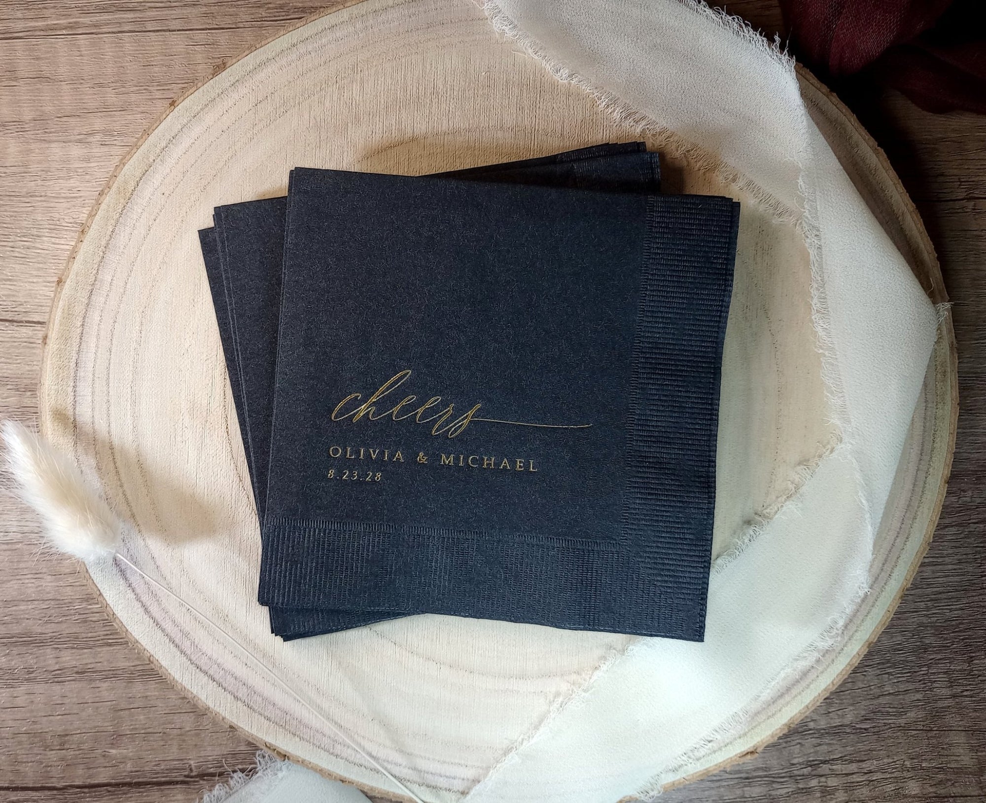 Black napkins with 'Cheers Olivia & Michael' text on a wooden surface