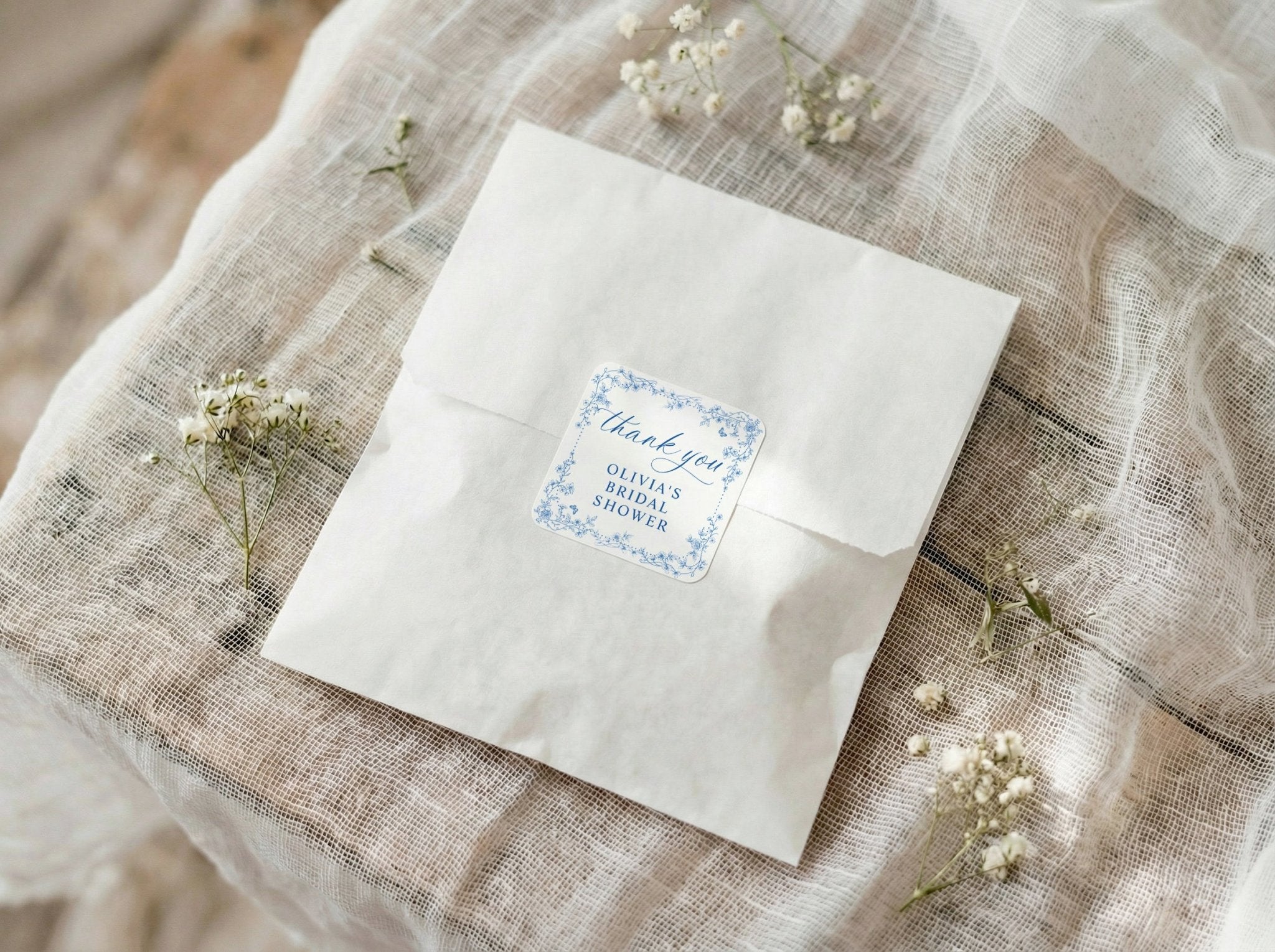 White envelope with a blue floral label on a textured fabric background