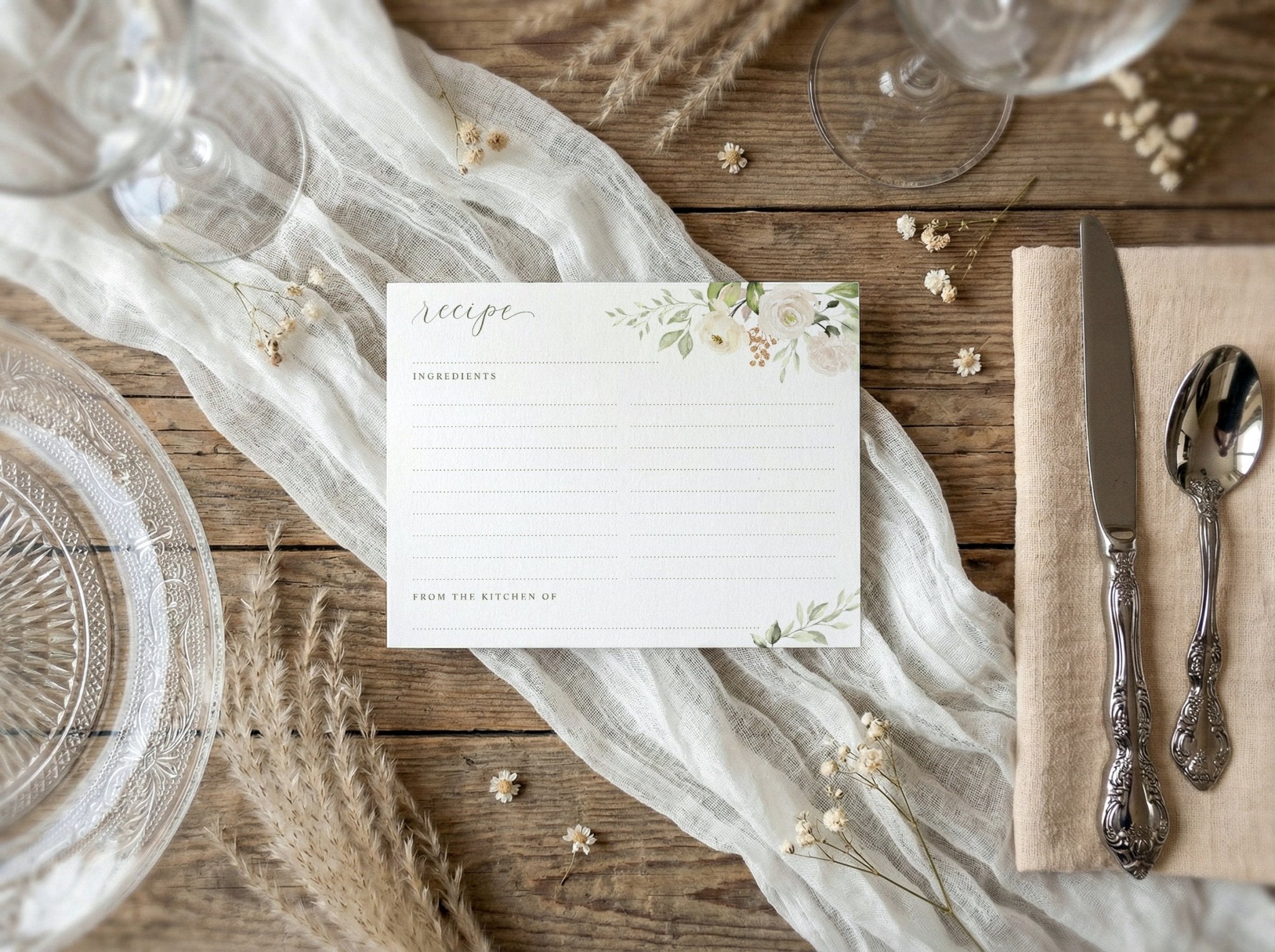 Table setting with a recipe card, silverware, and decorative elements on a wooden surface.