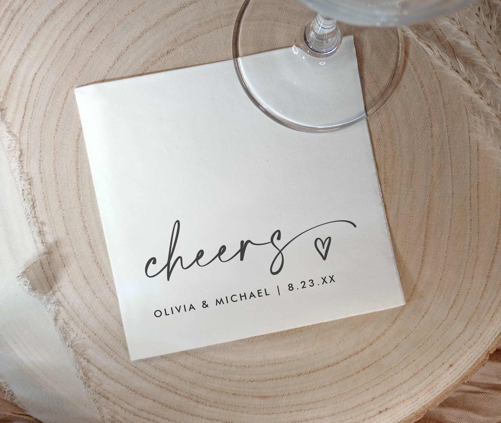 Personalized 'cheers' napkins with a heart and names on a wooden surface
