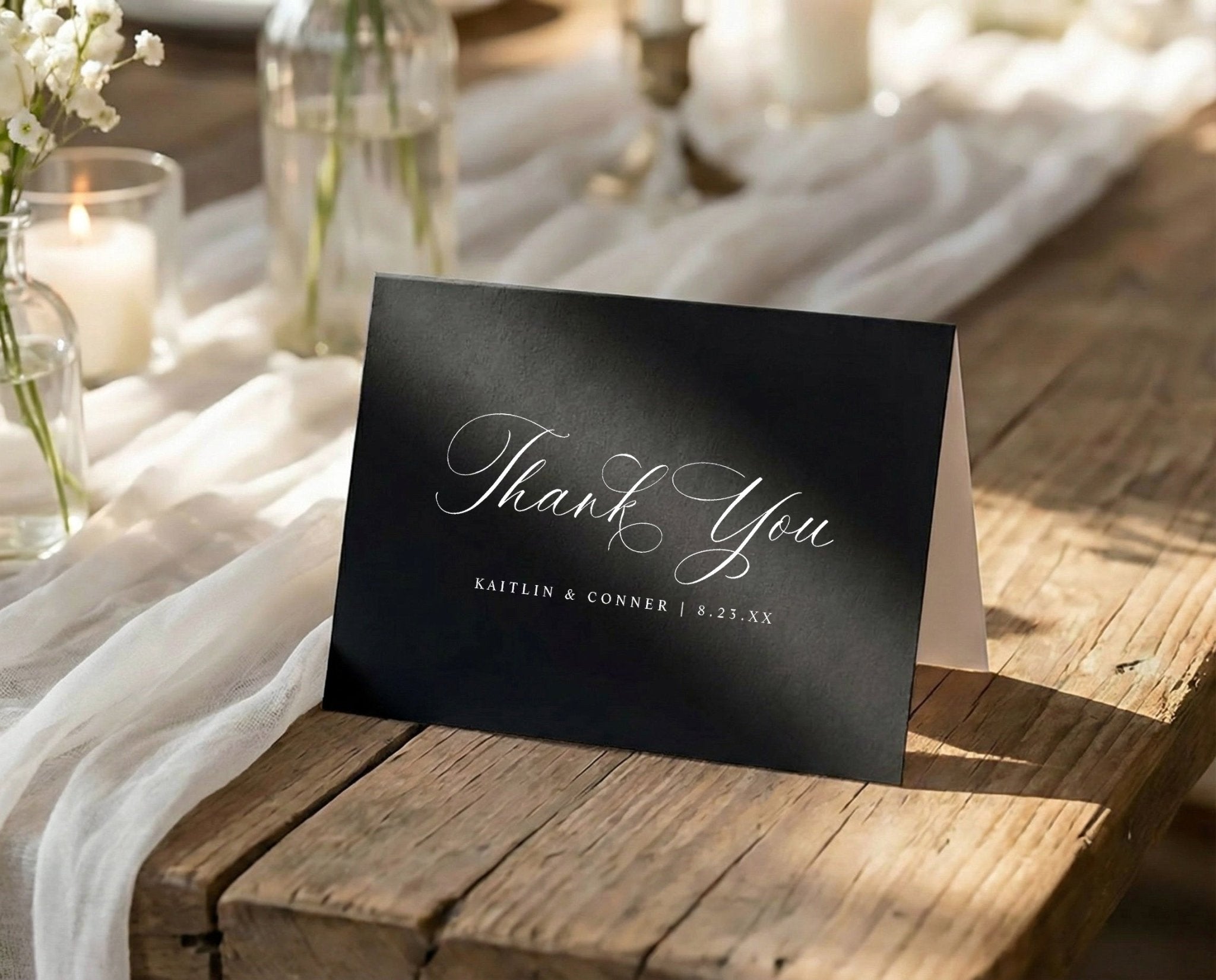 Black card with 'Thank You' on a wooden table with white tablecloth