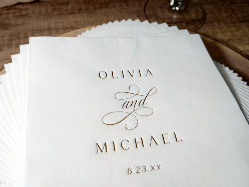 Stack of vintage-inspired custom foil-stamped wedding napkins with names and date in gold foil.