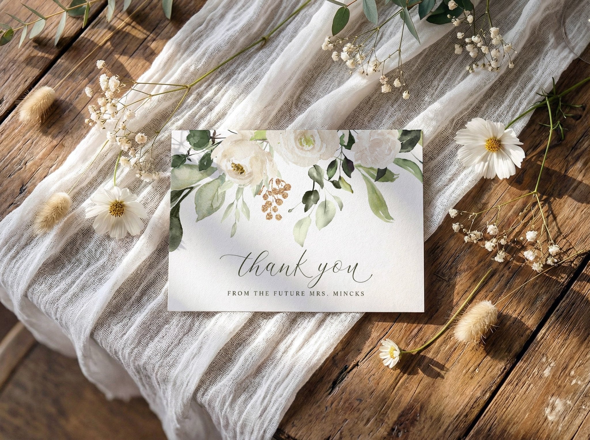 Thank You Card with floral design and 'thank you' message on a wooden surface with fabric and flowers.