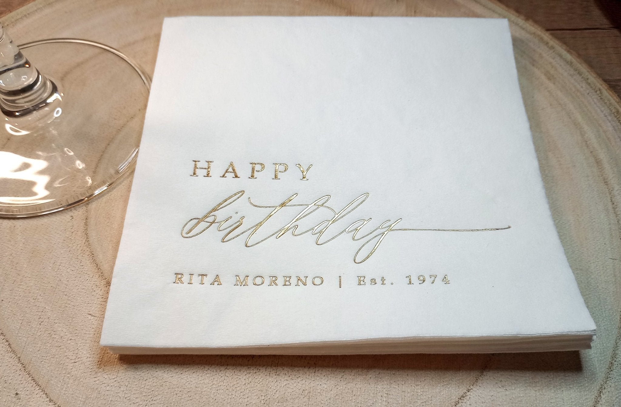 Close-up of gold foil Happy Birthday napkin with personalized name and established year.