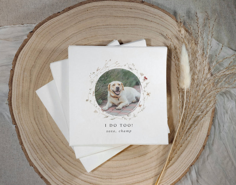 Stack of wedding napkins with a dog photo and text on a wooden surface
