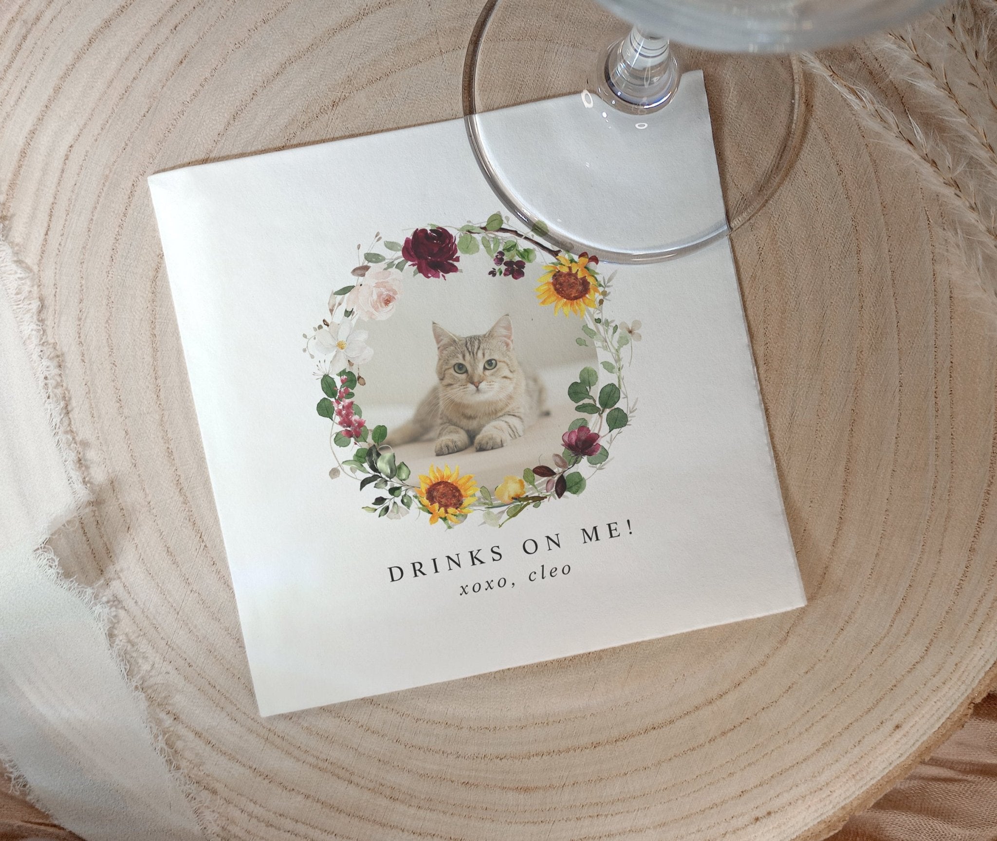 Pet photo napkins with a cat illustration and 'Drinks on Me!' text on a wooden surface.
