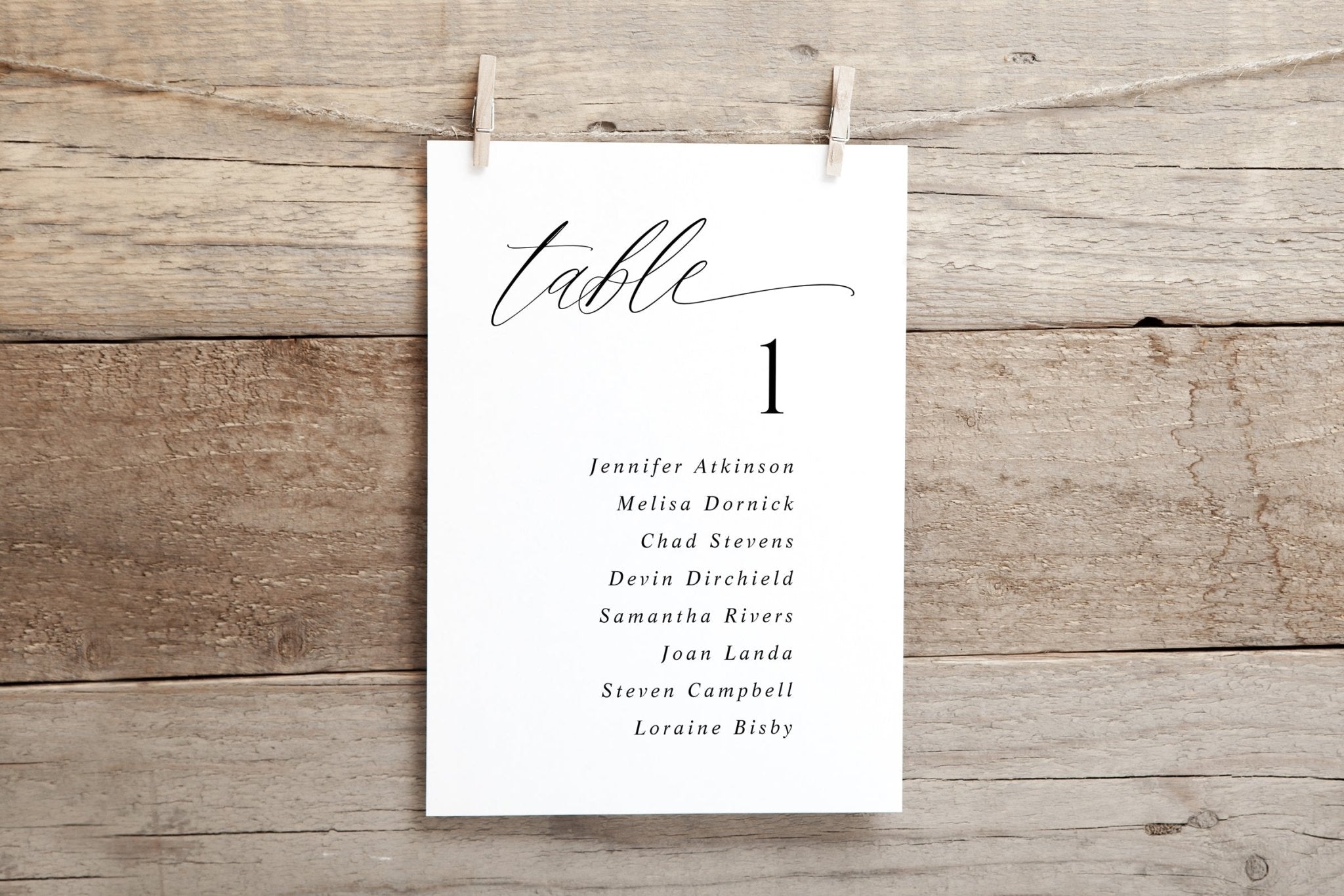 White table assignment card with names on a wooden background