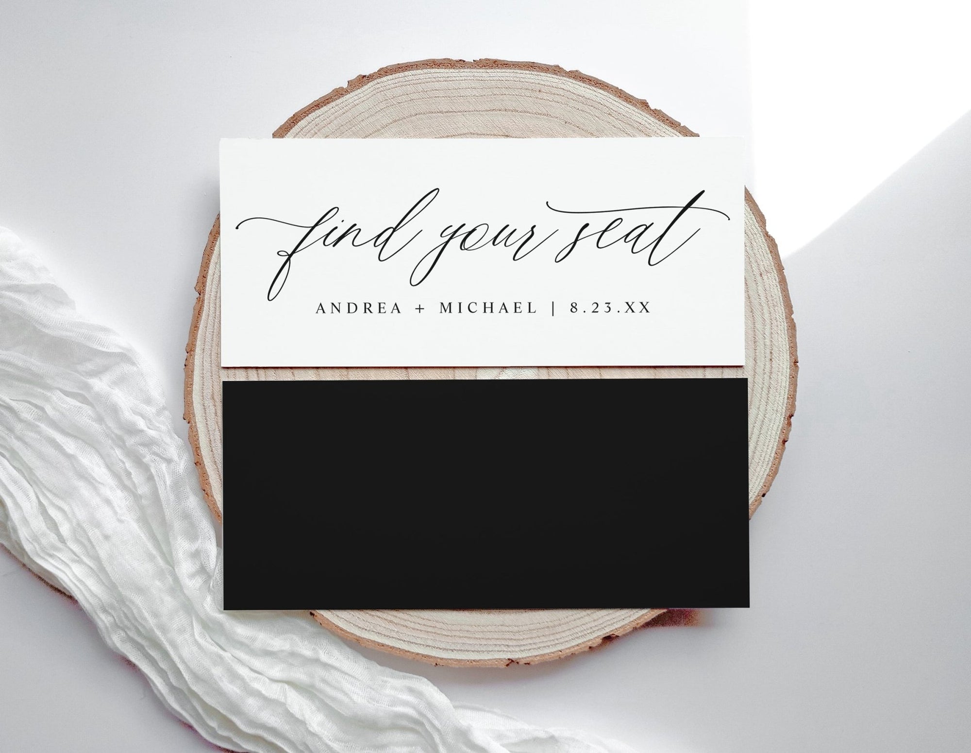 Wedding seating card with 'find your seat' text on a wooden slice and white fabric background