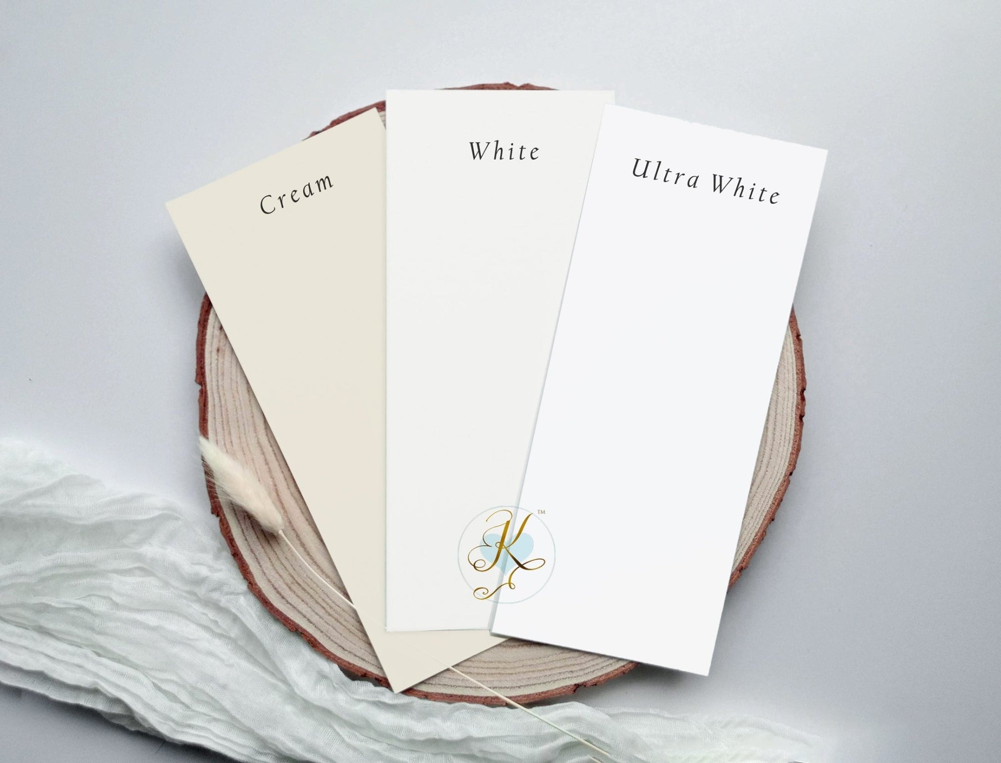 Three sheets of paper labeled 'Cream', 'White', and 'Ultra White' on a wooden board.