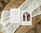 Two anniversary invitations on a wooden surface with white fabric