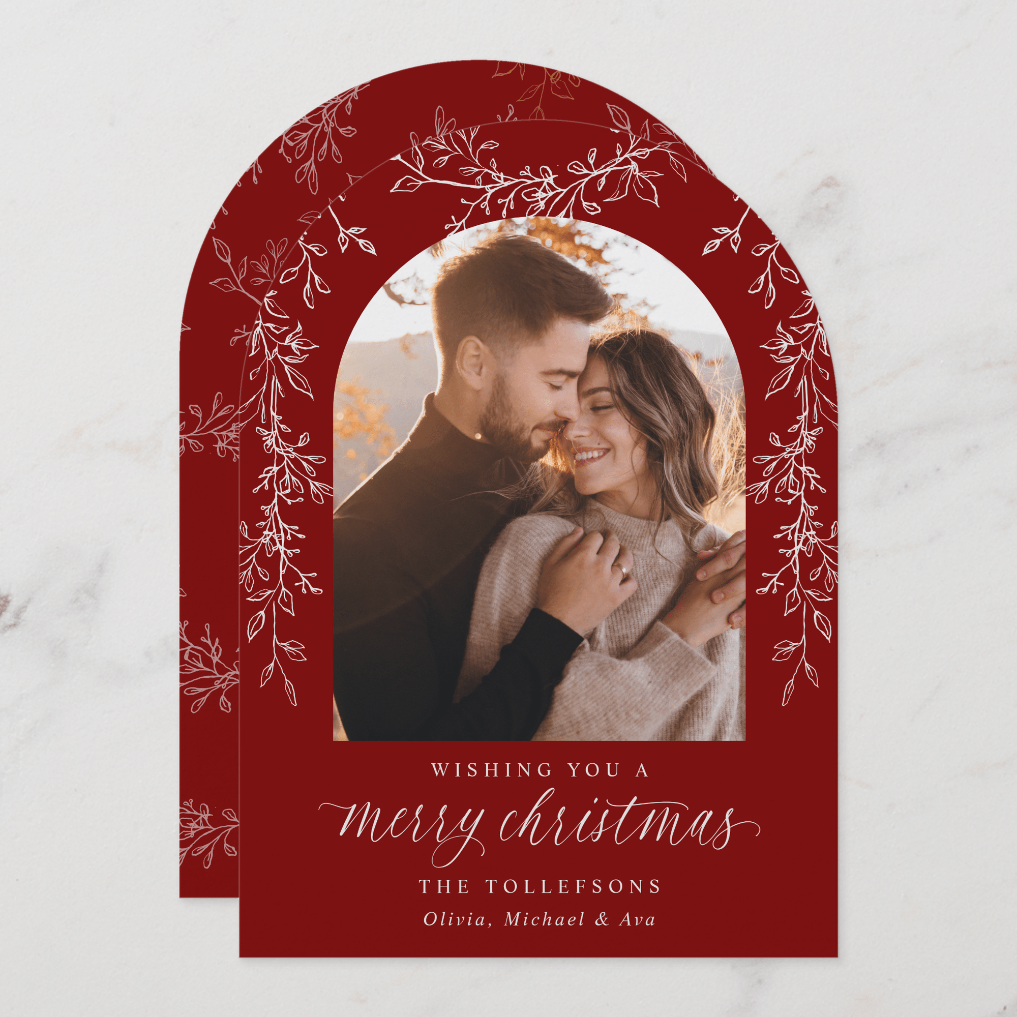 Christmas card with a red arch frame featuring a couple and text.