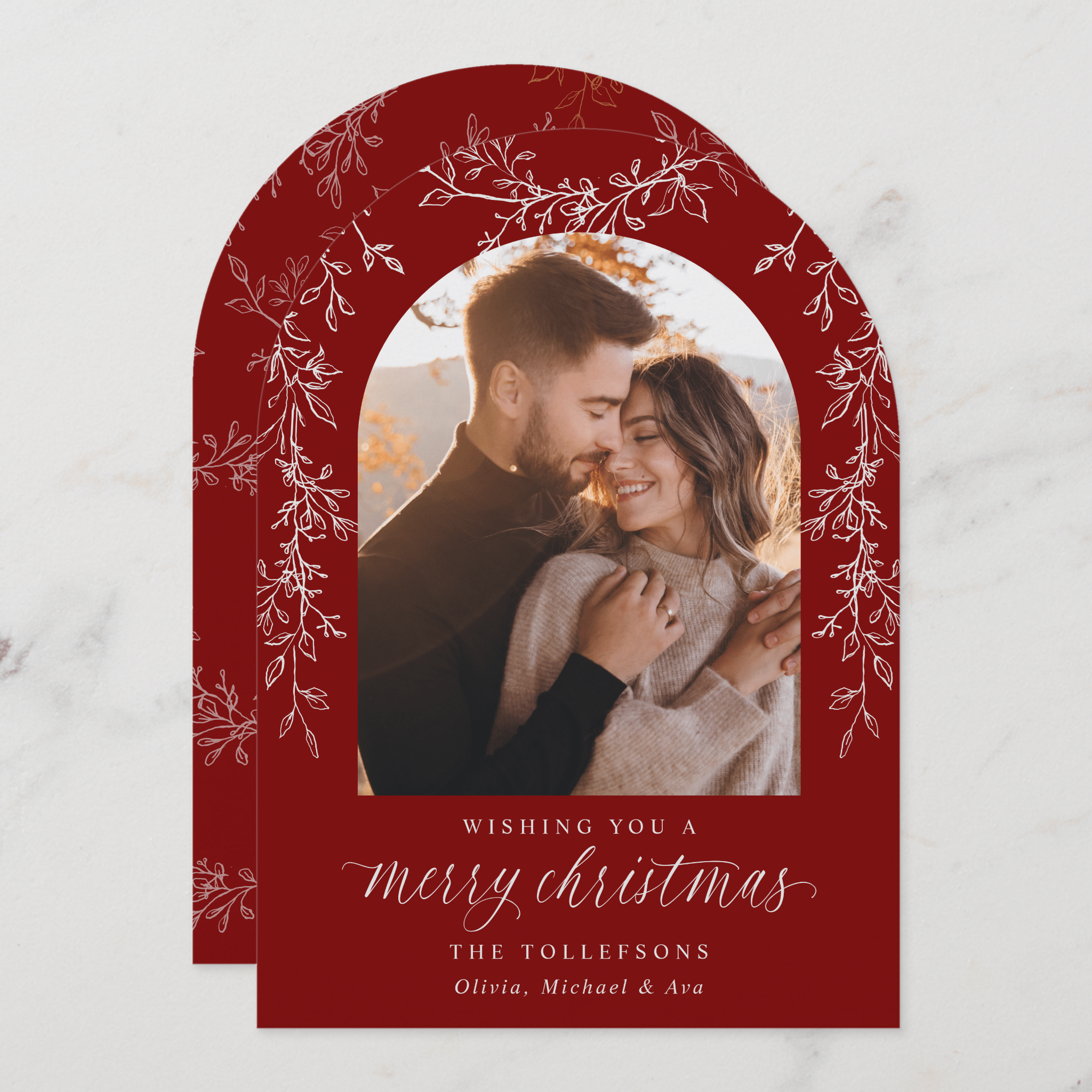 Christmas card with a red arch frame featuring a couple and text.