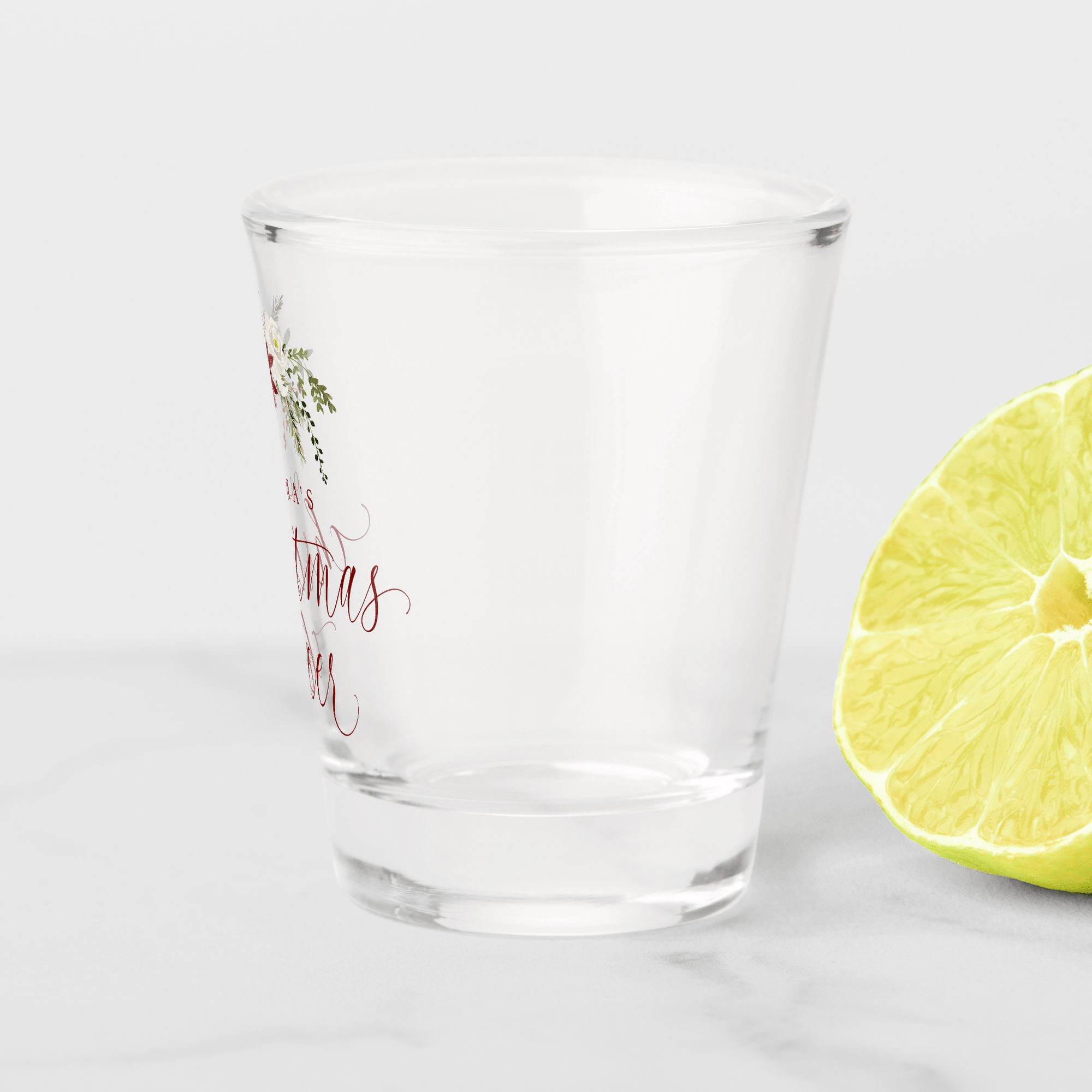 Trendy holiday shot glass with greenery bouquet design and custom name.
