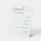 Modern calligraphy cupcake flavors sign displayed at a wedding dessert bar.