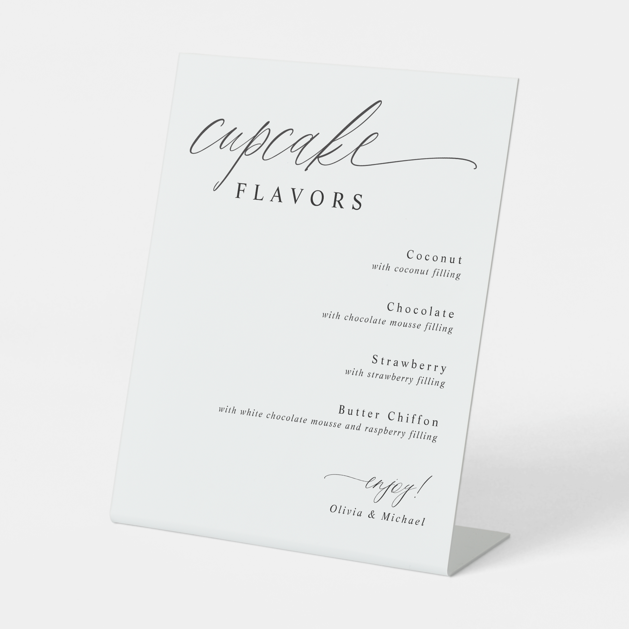Modern calligraphy cupcake flavors sign displayed at a wedding dessert bar.