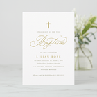 Baptism invitation card with gold text on a white background, blurred flowers in the background.