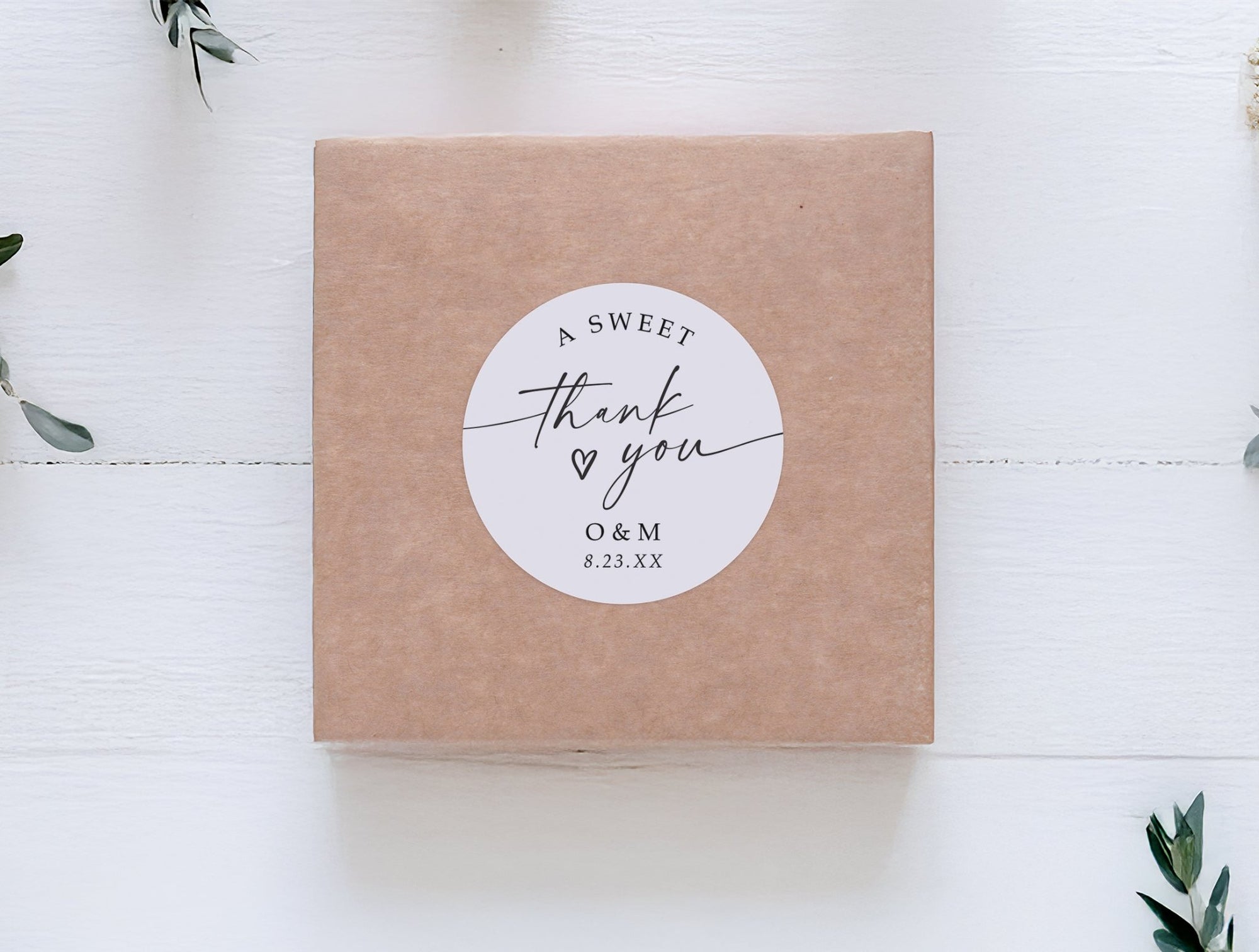 Kraft wedding favor box sealed with personalized 2-inch circle sticker that says “a sweet thank you,” customized with initials and wedding date.