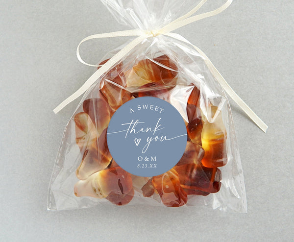Personalized 2-inch round wedding favor sticker with “a sweet thank you” in script, attached to clear candy bag, customized with couple’s initials and date.