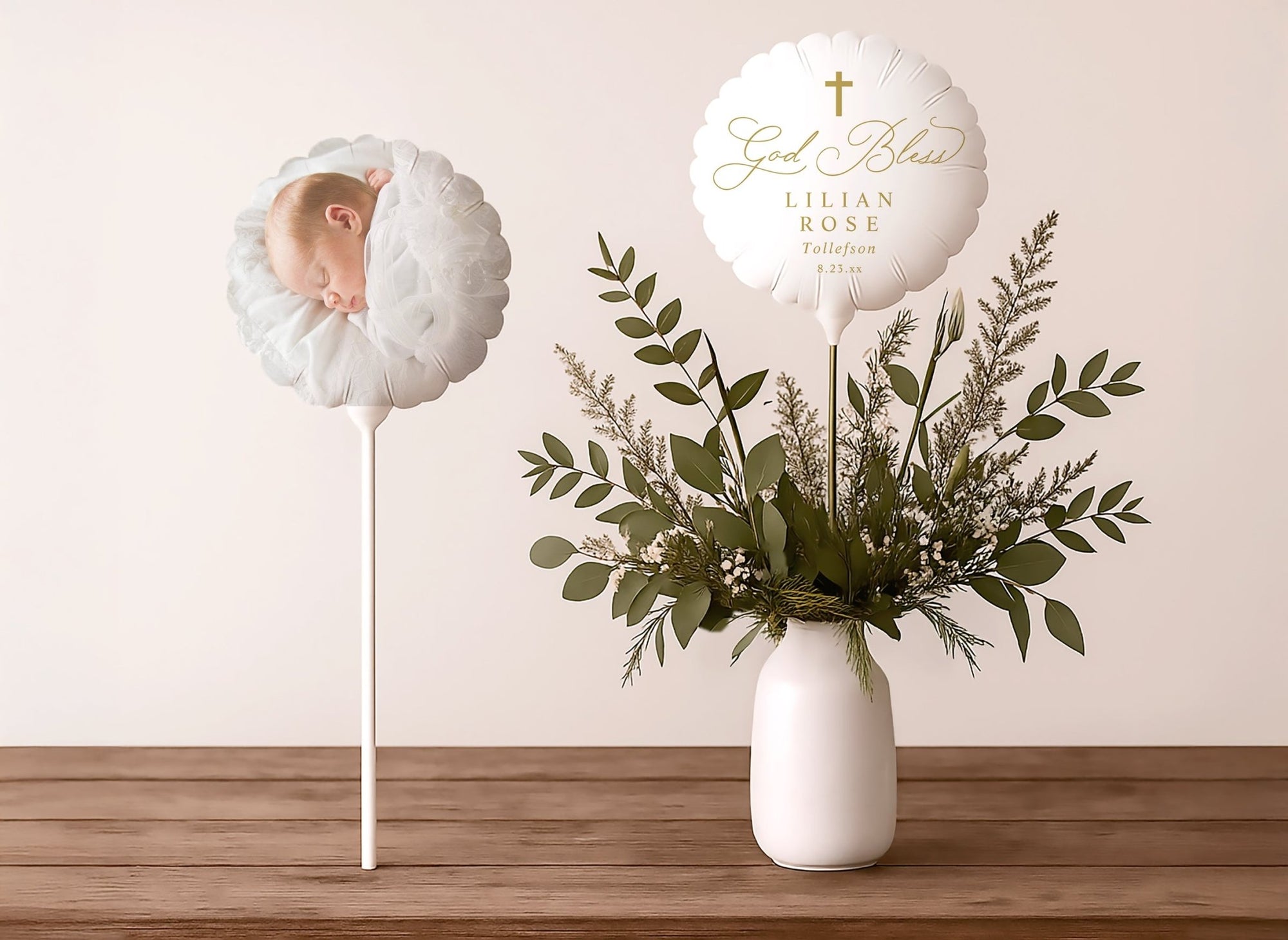 Elegant baptism balloons with 'God Bless' text and floral arrangement on a wooden surface.