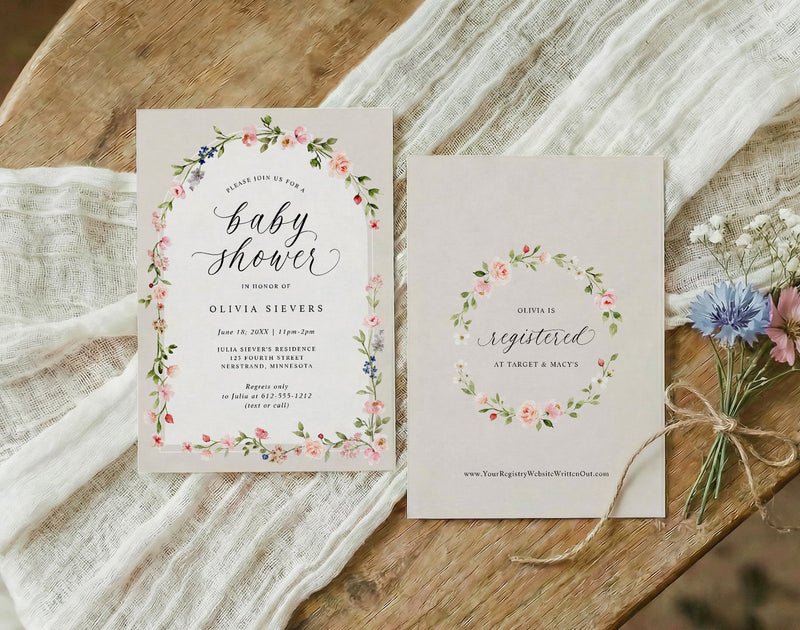 Baby shower invitations with floral designs on a wooden surface