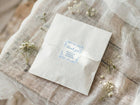 White envelope with a blue floral label on a textured fabric background