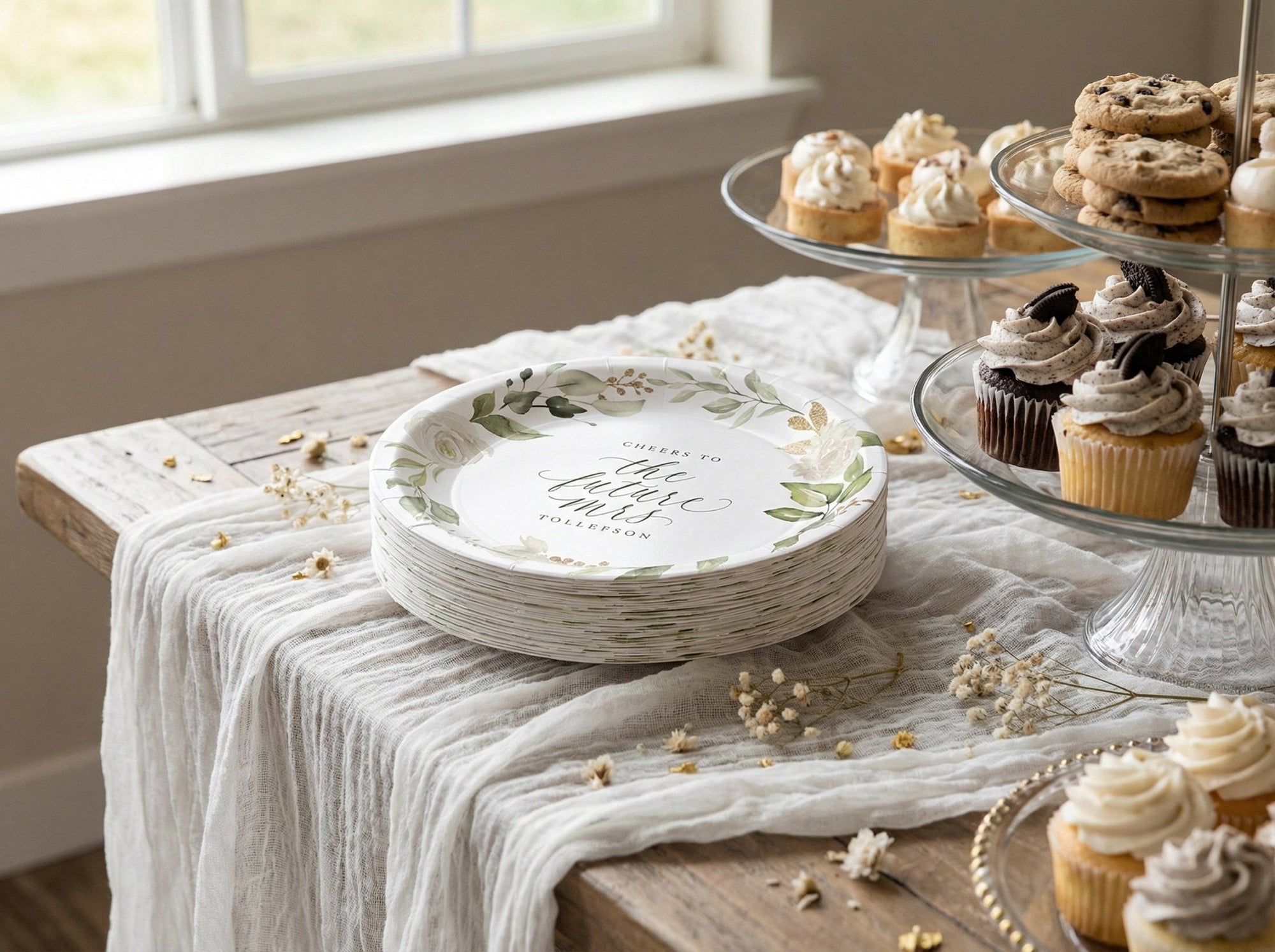 Decorative bridal shower plates with floral designs on a table with cupcakes.