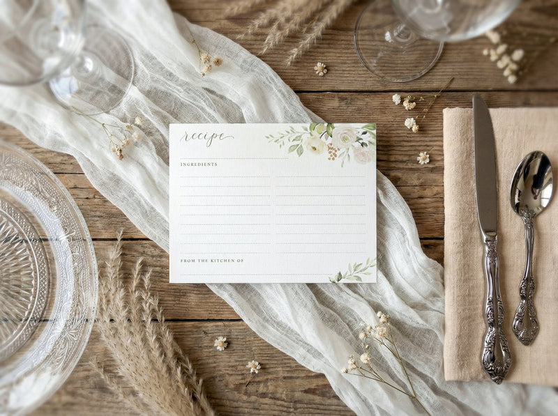 Table setting with a recipe card, silverware, and decorative elements on a wooden surface.