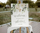 Welcome sign for a bridal shower with floral design on an easel outdoors.