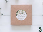 round thank you sticker for bridal showers shown on a kraft box with greenery