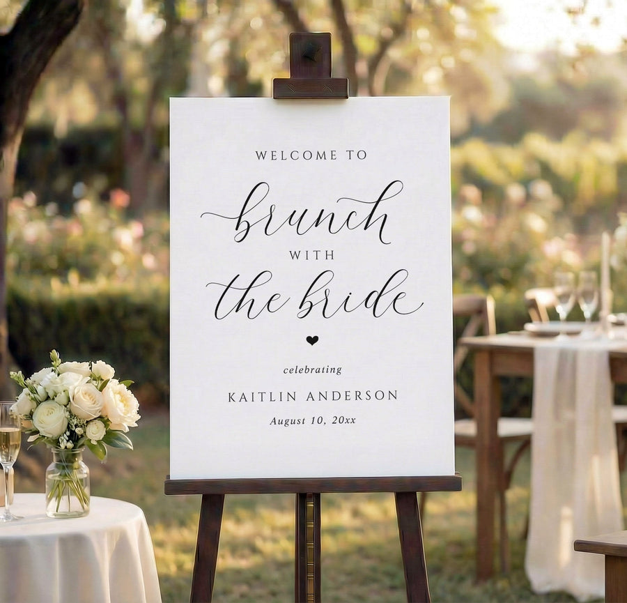 Wedding brunch welcome sign on an easel with outdoor wedding setup in the background.