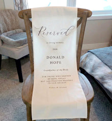 Chair with a reserved seat sign for Donald Hope in a room with chairs and a window.
