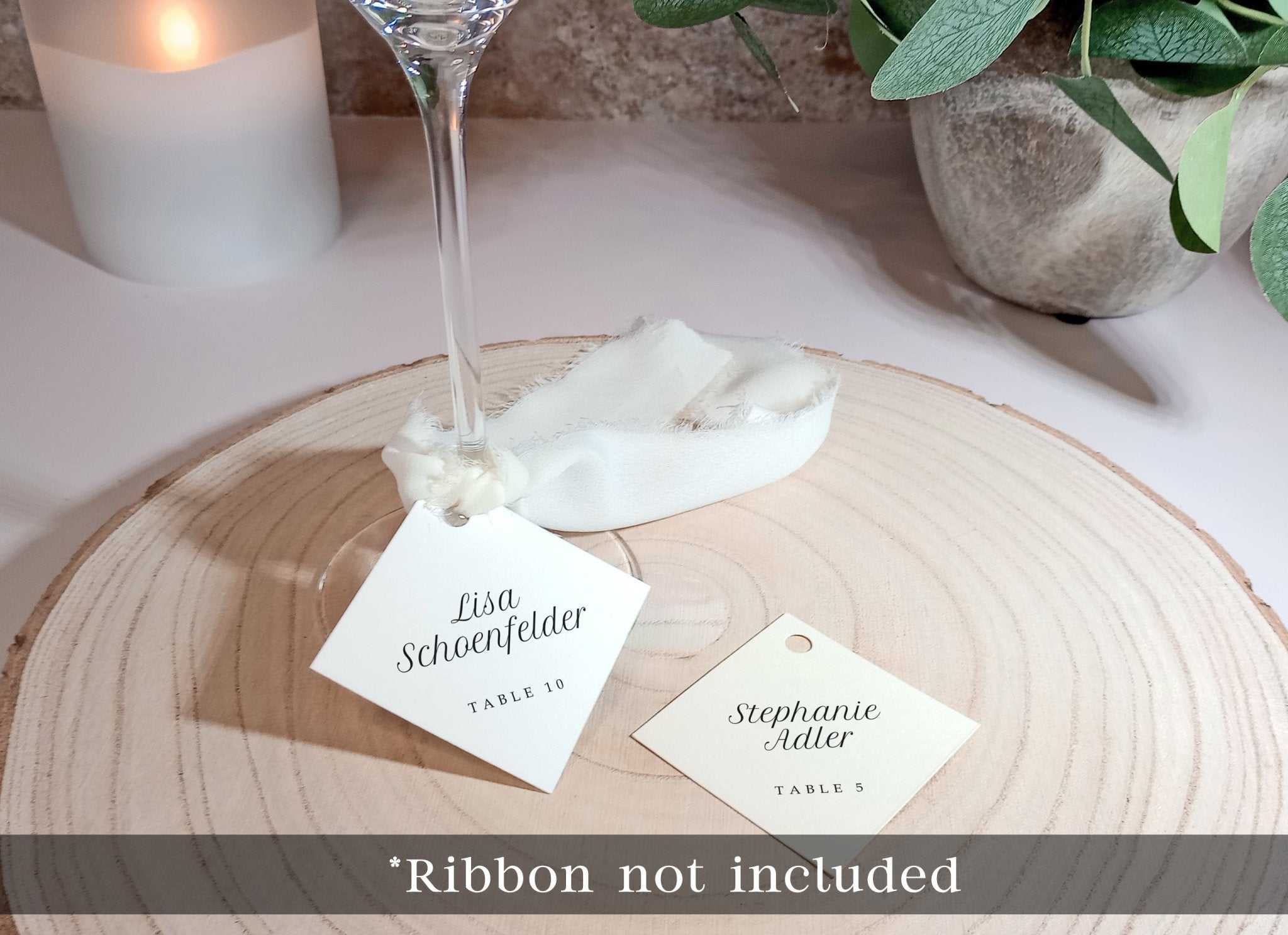 minimalist wedding glass tags with guest names and table numbers tied with ribbon