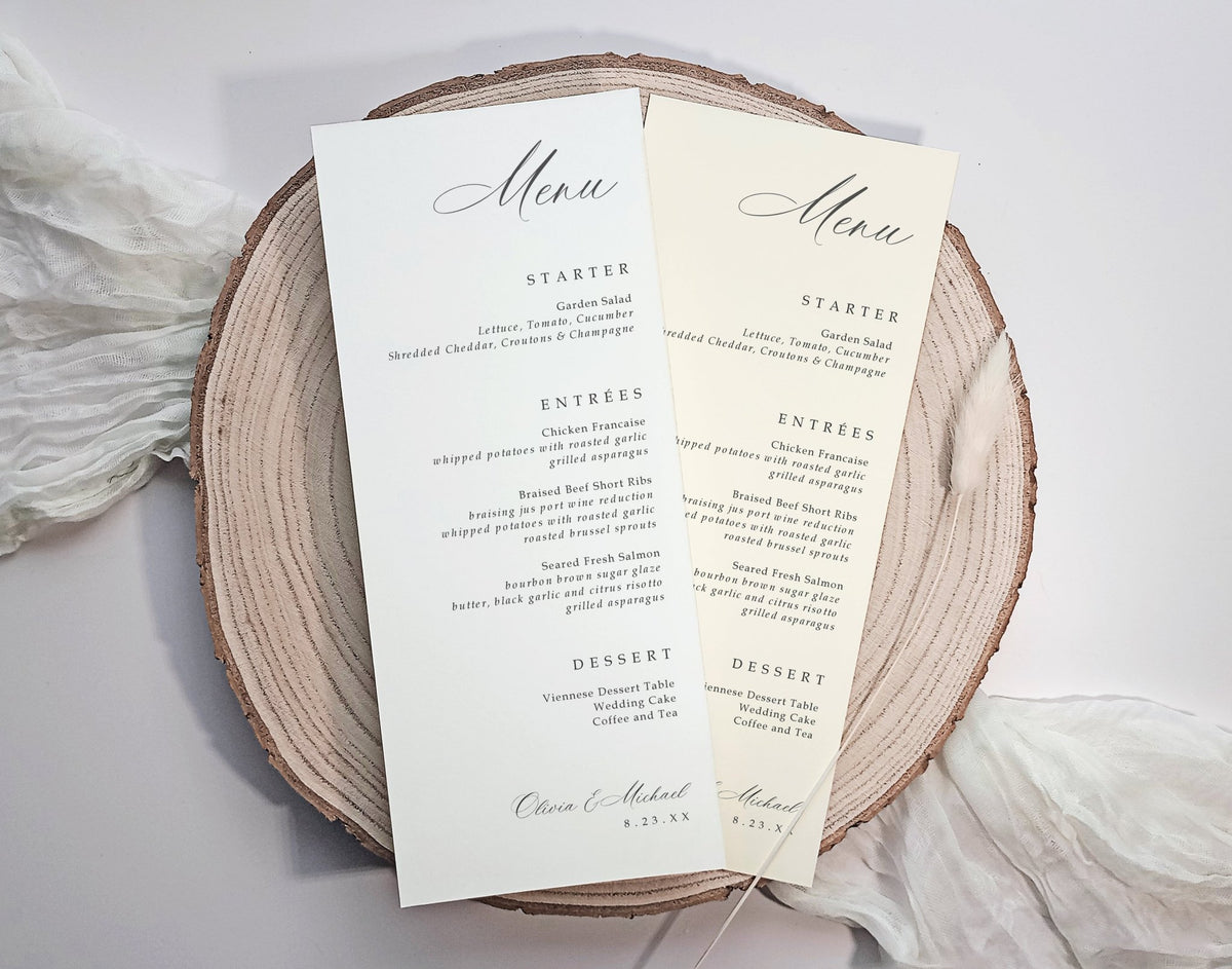 Two elegant wedding menu cards custom printed with black script and serif text on cream paper, displayed on a round natural wood slice coaster with soft white fabric in the background.