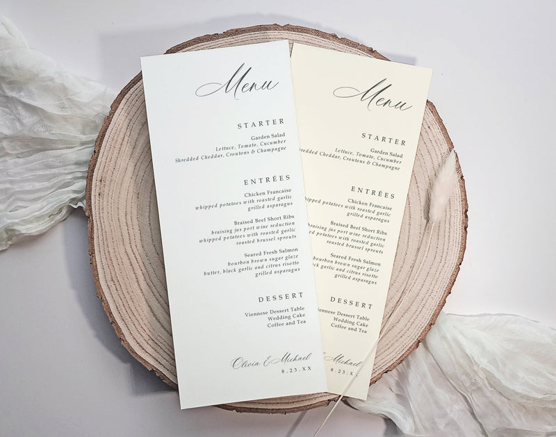 Two elegant wedding menu cards custom printed with black script and serif text on cream paper, displayed on a round natural wood slice coaster with soft white fabric in the background.
