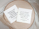 Two custom wedding napkins with love note messages in script font on wood plate