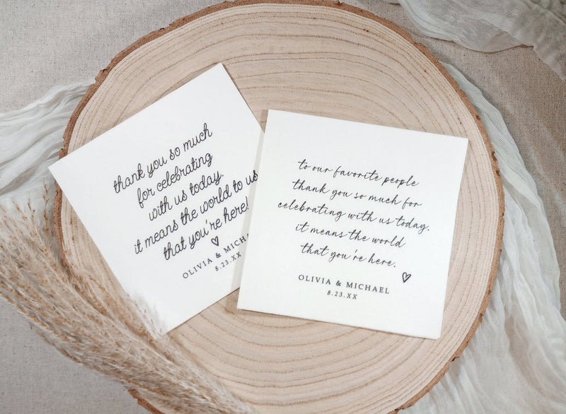 Two custom wedding napkins with love note messages in script font on wood plate
