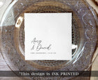 black ink printed wedding napkin with names in elegant handwriting script on clear charger plate