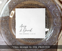 black ink printed wedding napkin with names in elegant handwriting script on clear charger plate