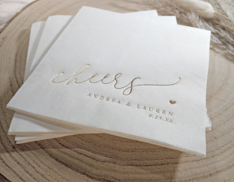 Stack of white napkins with gold text on a wooden surface