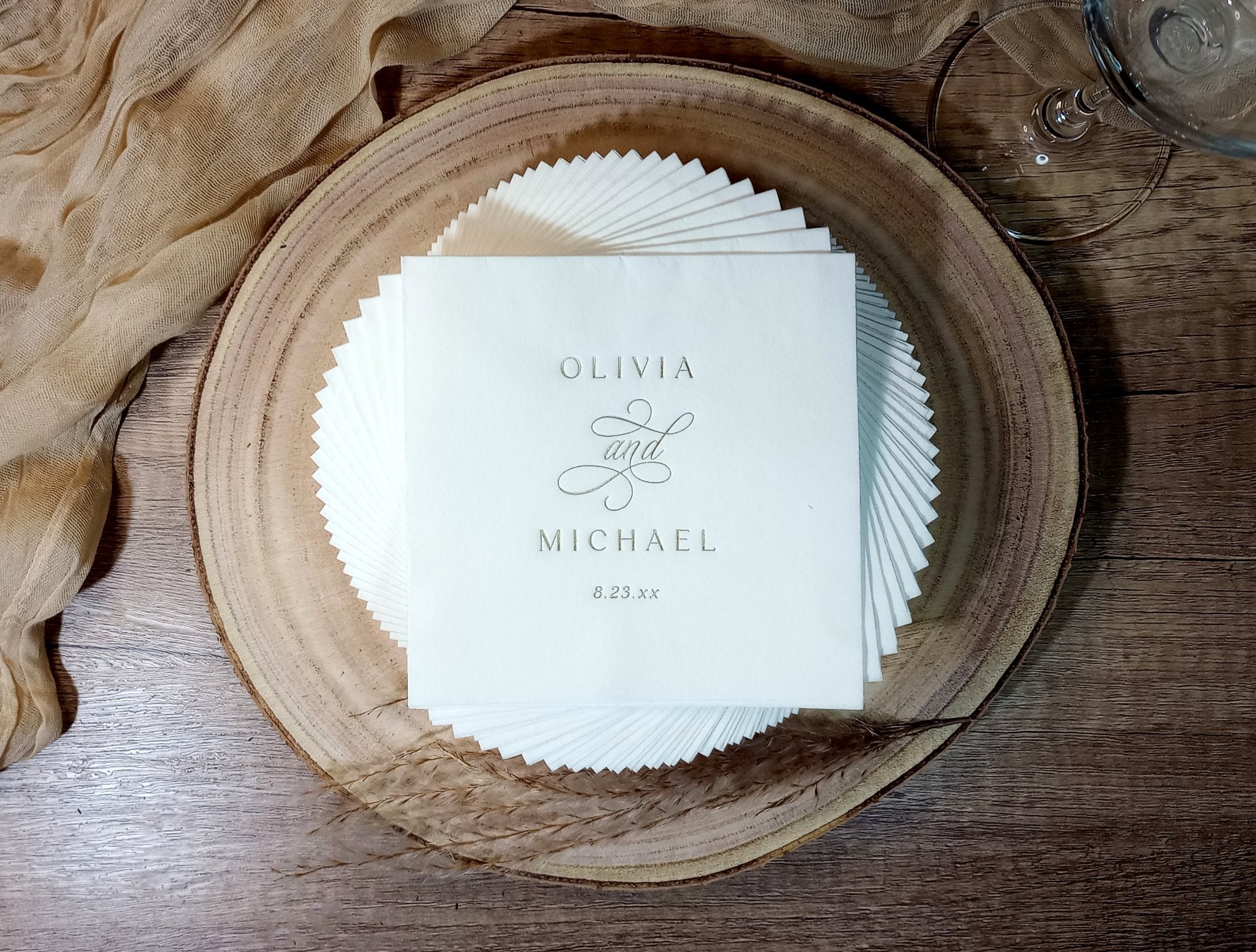 Elegant custom wedding napkin with vintage monogram design placed on dinner plate, stamped in gold foil.