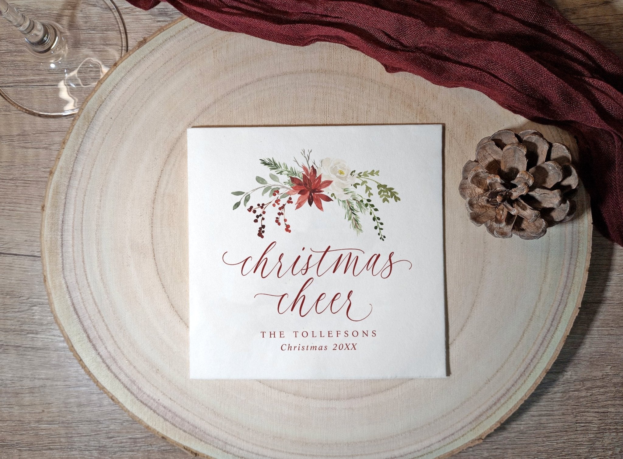 Red and green botanical Christmas napkin with elegant holiday script.