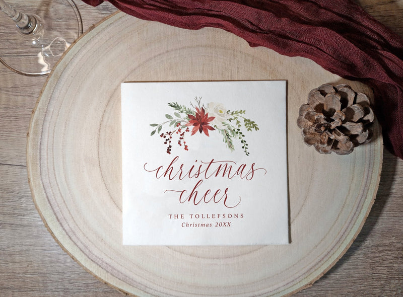 Red and green botanical Christmas napkin with elegant holiday script.