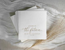 Elegant gold cocktail napkin with “cheers to the future” in modern calligraphy script.