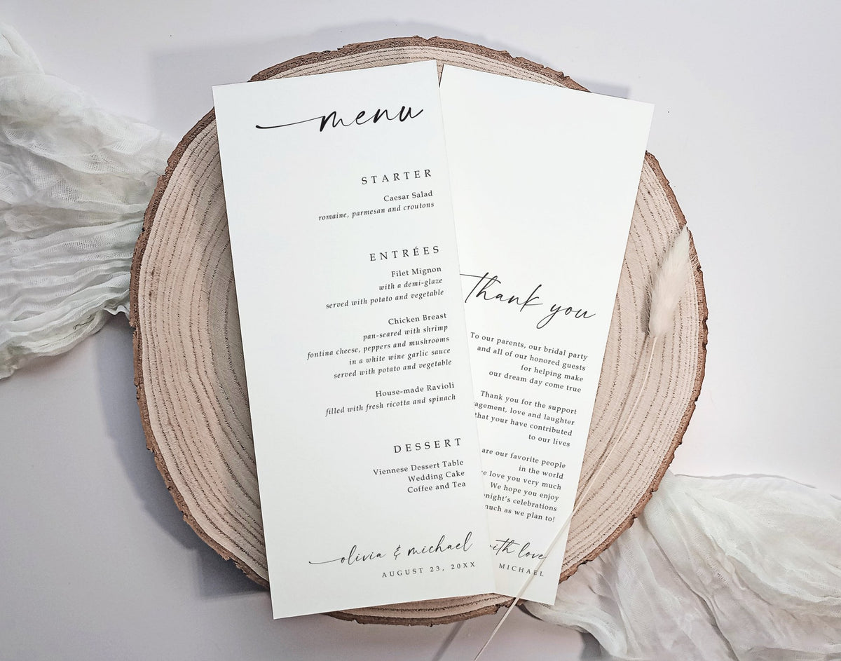 A wedding menu and thank you card set printed on white cardstock, styled on a round natural wood slice with soft white fabric in the background.
