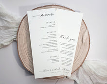A wedding menu and thank you card set printed on white cardstock, styled on a round natural wood slice with soft white fabric in the background.
