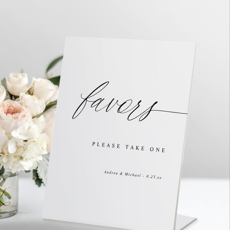 Standing “Favors” wedding sign in romantic calligraphy, displayed on a favor table.