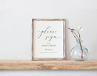 Framed guest book sign on a wooden shelf with a vase containing a plant